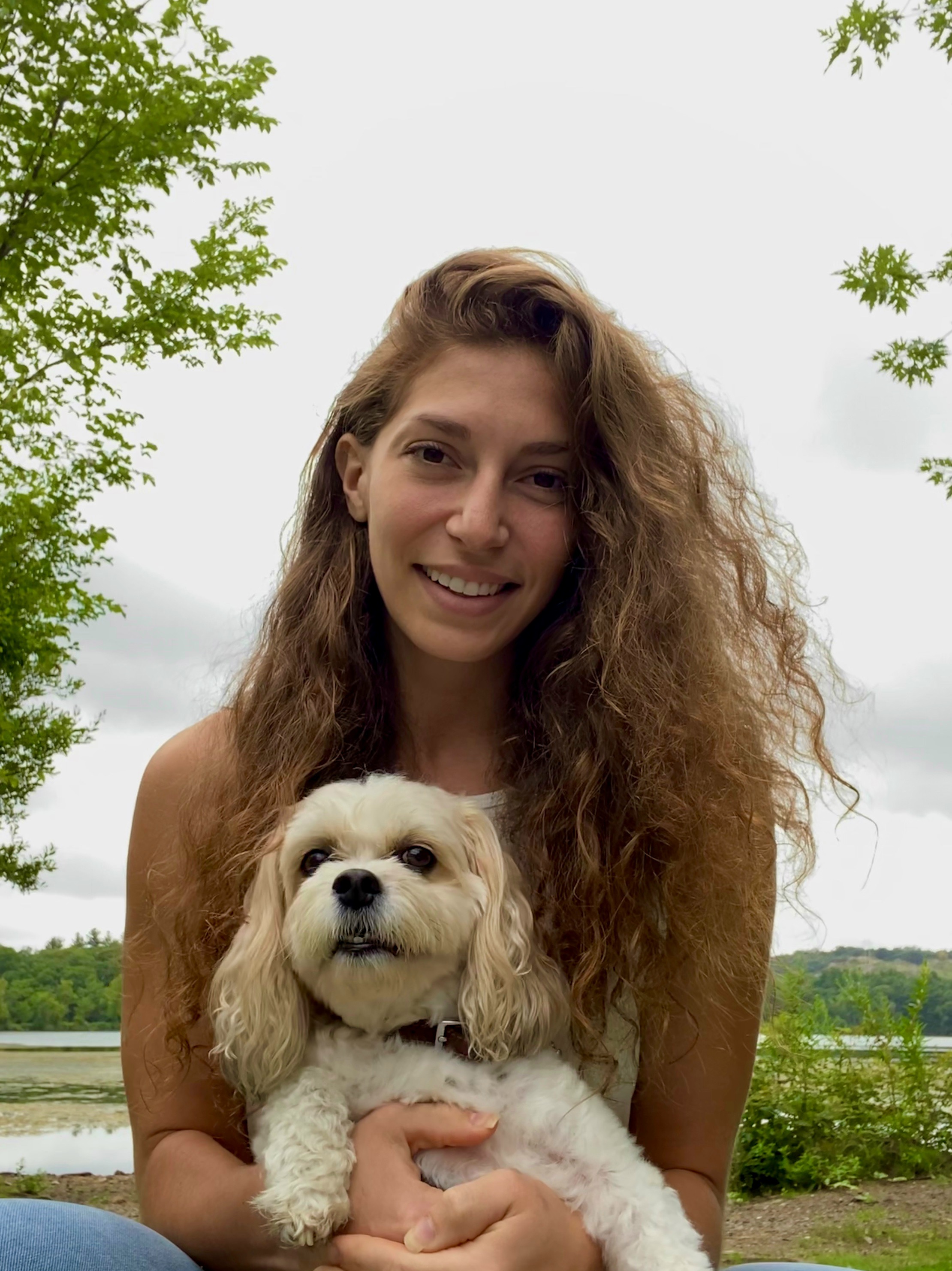 Jena holding her dog by the water